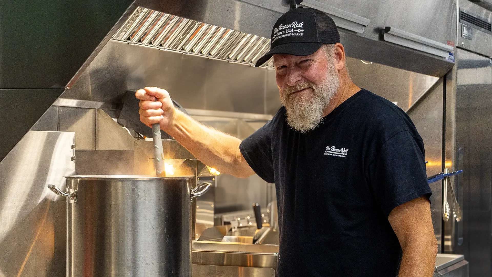 brass rail employee stirs a pot of sauce at allentown farmers market