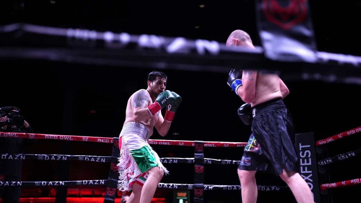 gustavo morales in white and green shorts stalks forward with gloves raised toward chevy bridges in black shorts under the dazn and boxfest signage at archer music hall