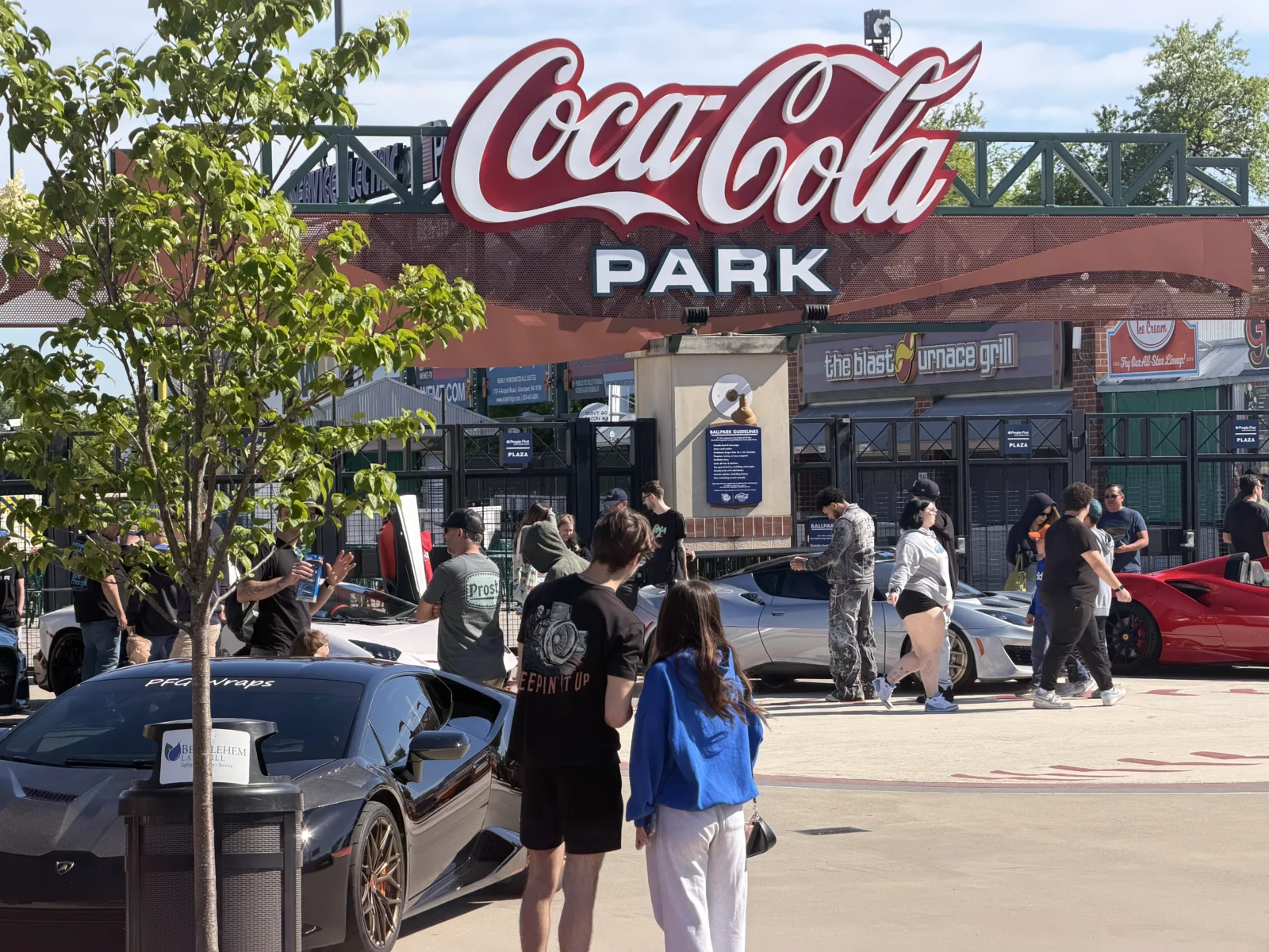 A row of sports cars with show-goers walking past.