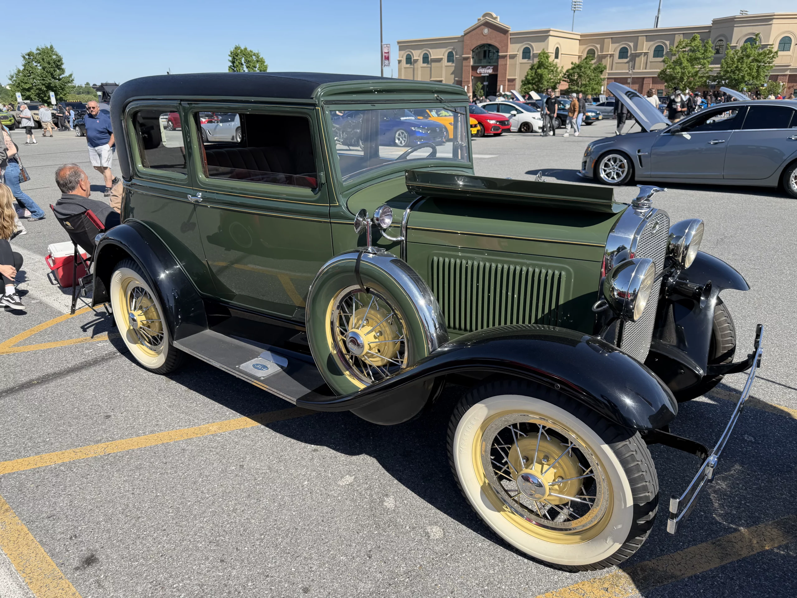 A green early-1930s Ford Model A sedan parked at a car show