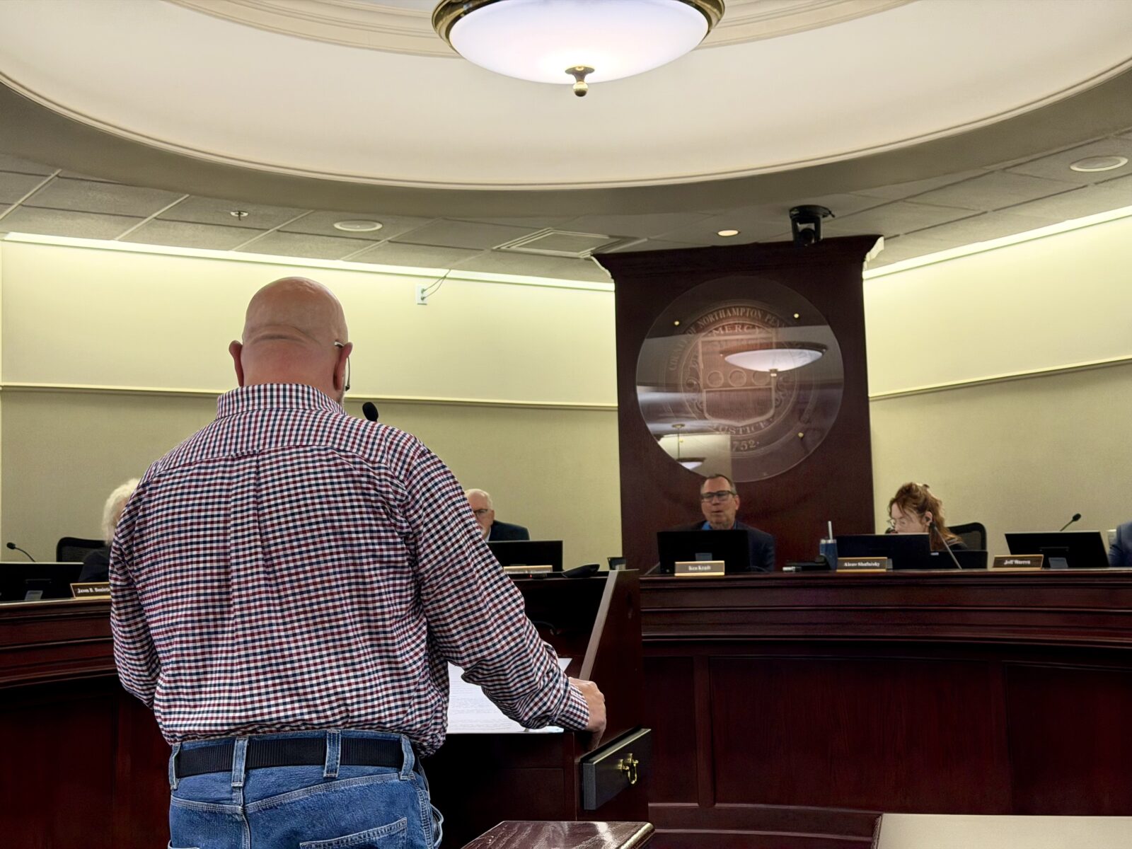 wilson borough mayor don barrett, photographed from behind, speaks at a lectern facing northampton county council members seated at the dais