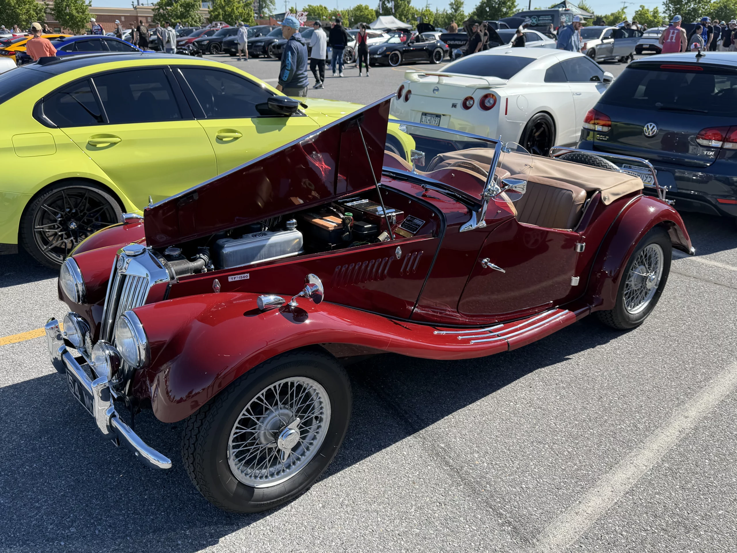 A maroon MG TF 1500 roadster with a white Nissan GT-R and a green BMW nearby
