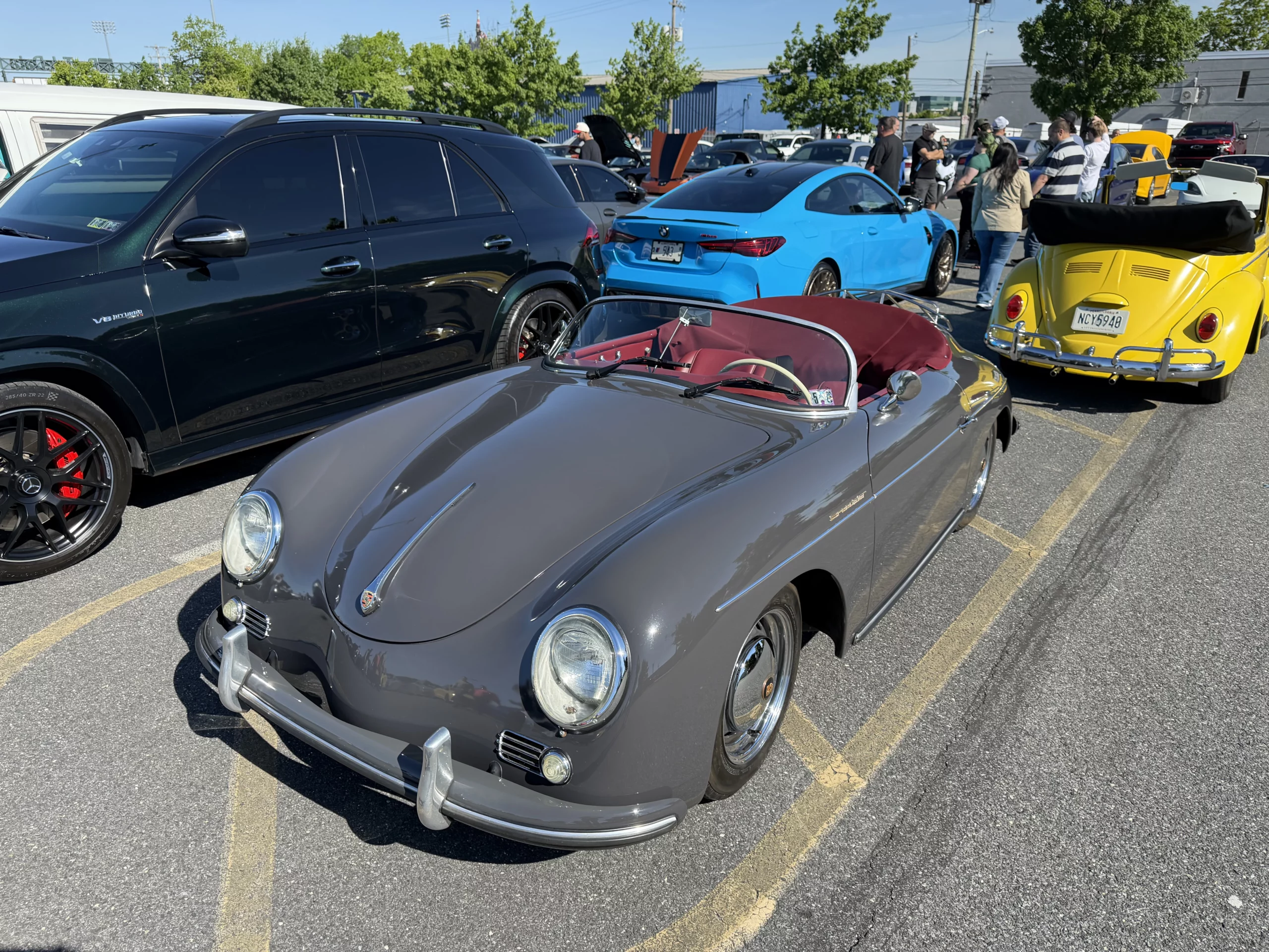 A Porsche 356 Speedster beside a yellow VW Beetle and other cars
