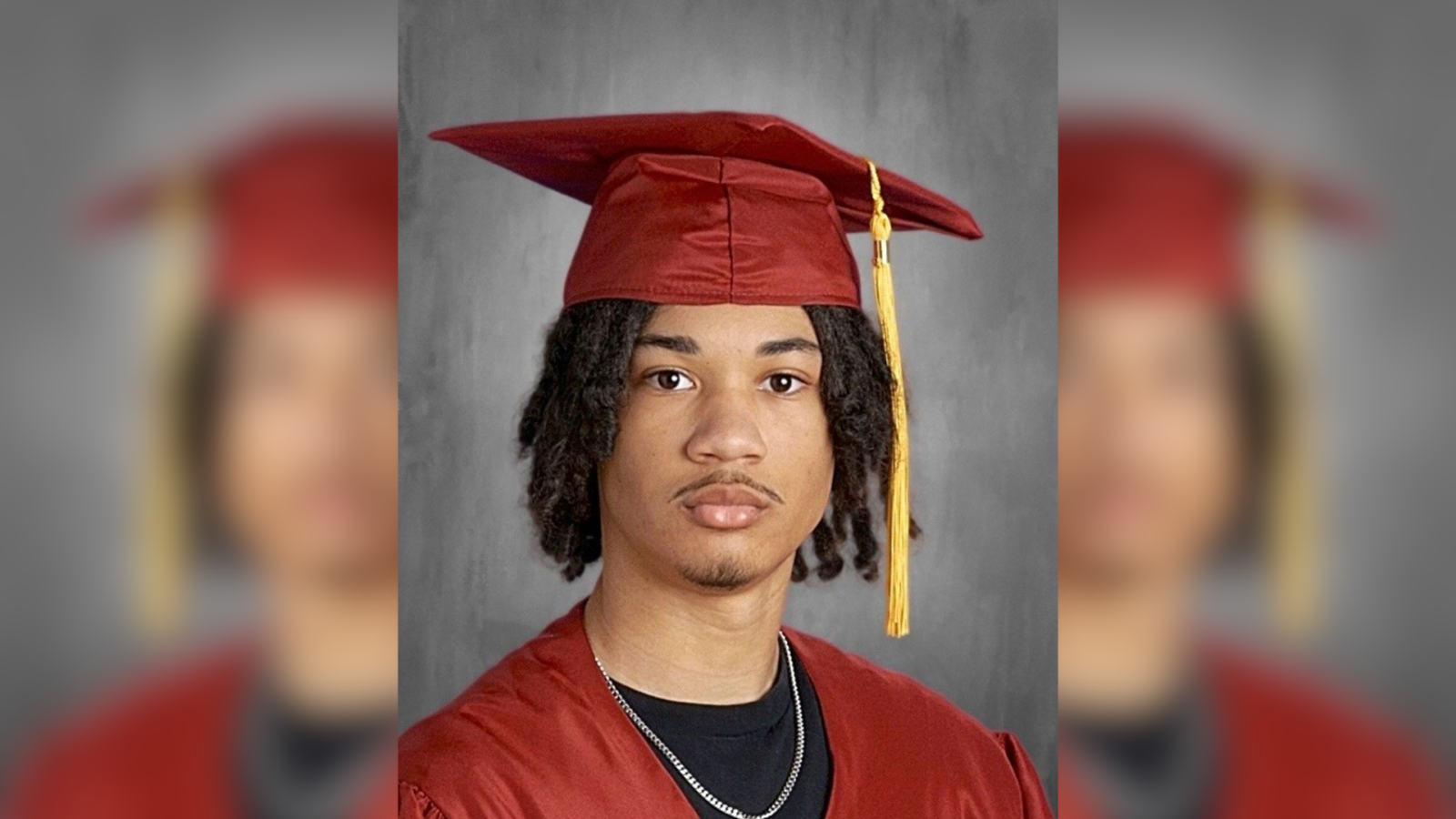 Tymell Millan-Mason poses for his Lincoln Leadership Academy Class of 2026 senior portrait, wearing a red graduation cap and gown with a gold tassel over a black t-shirt and silver chain.