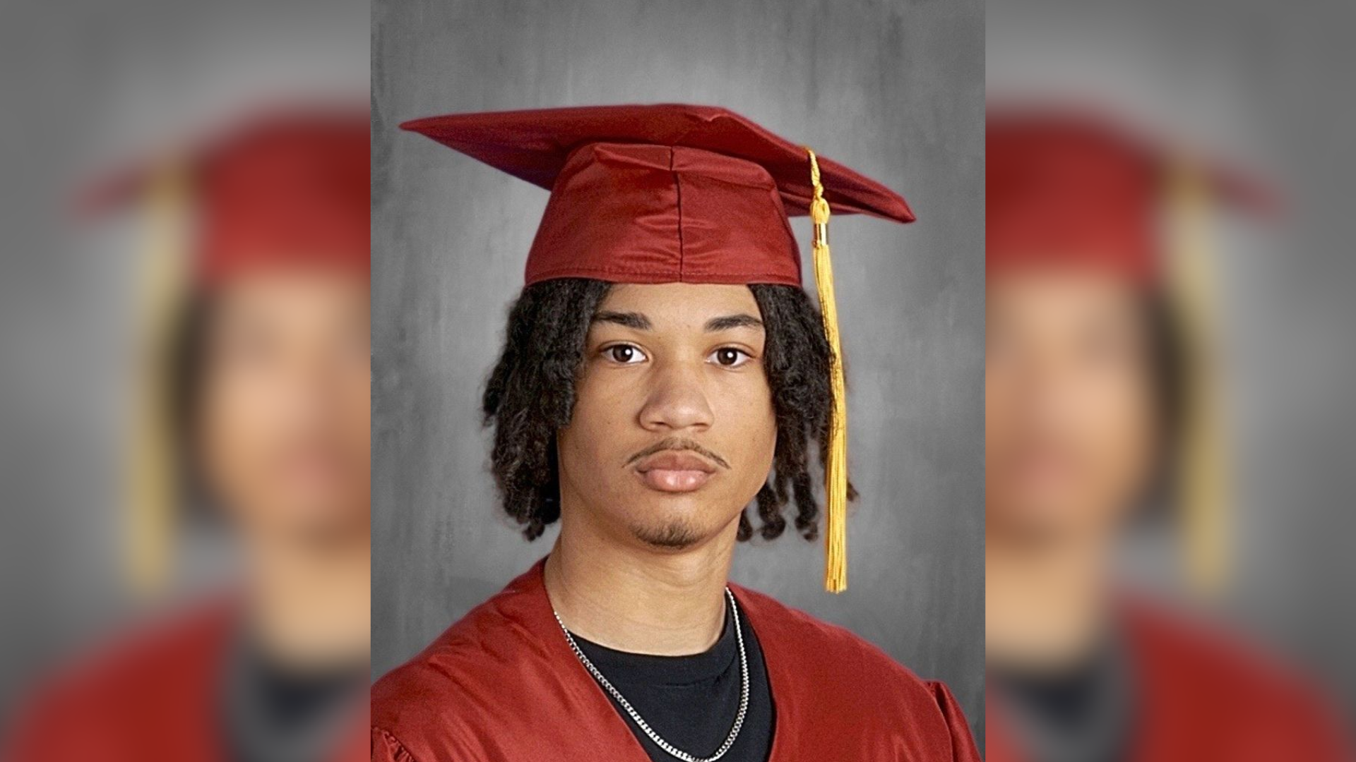 Tymell Millan-Mason poses for his Lincoln Leadership Academy Class of 2026 senior portrait, wearing a red graduation cap and gown with a gold tassel over a black t-shirt and silver chain.