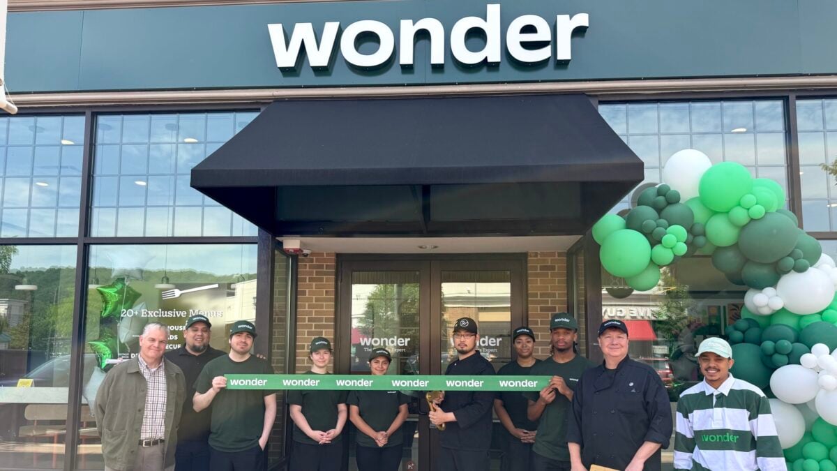 Wonder employees and an executive hold a green ribbon outside the new restaurant entrance.