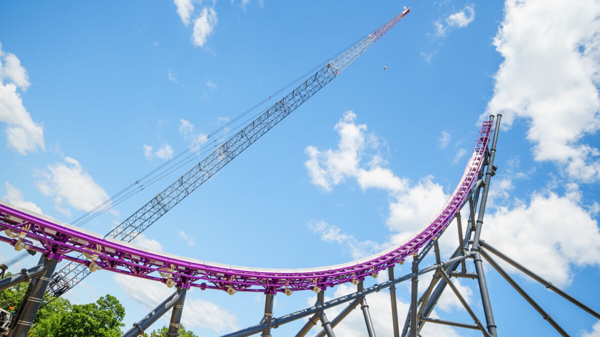 Purple roller coaster track and gray support beams rise beside a tall construction crane at Six Flags Great Adventure in Jackson, New Jersey.