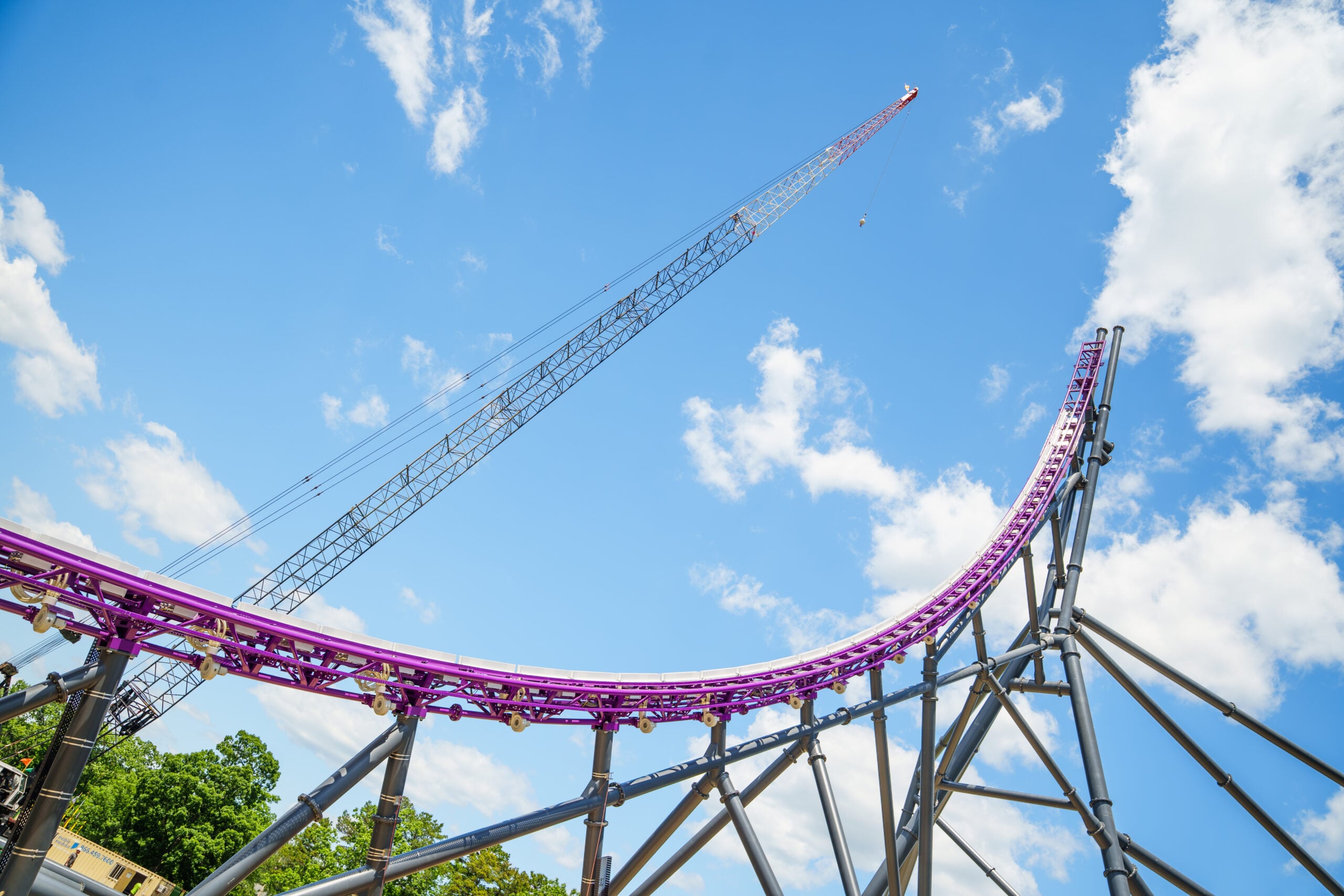Purple roller coaster track and gray support beams rise beside a tall construction crane at Six Flags Great Adventure in Jackson, New Jersey.