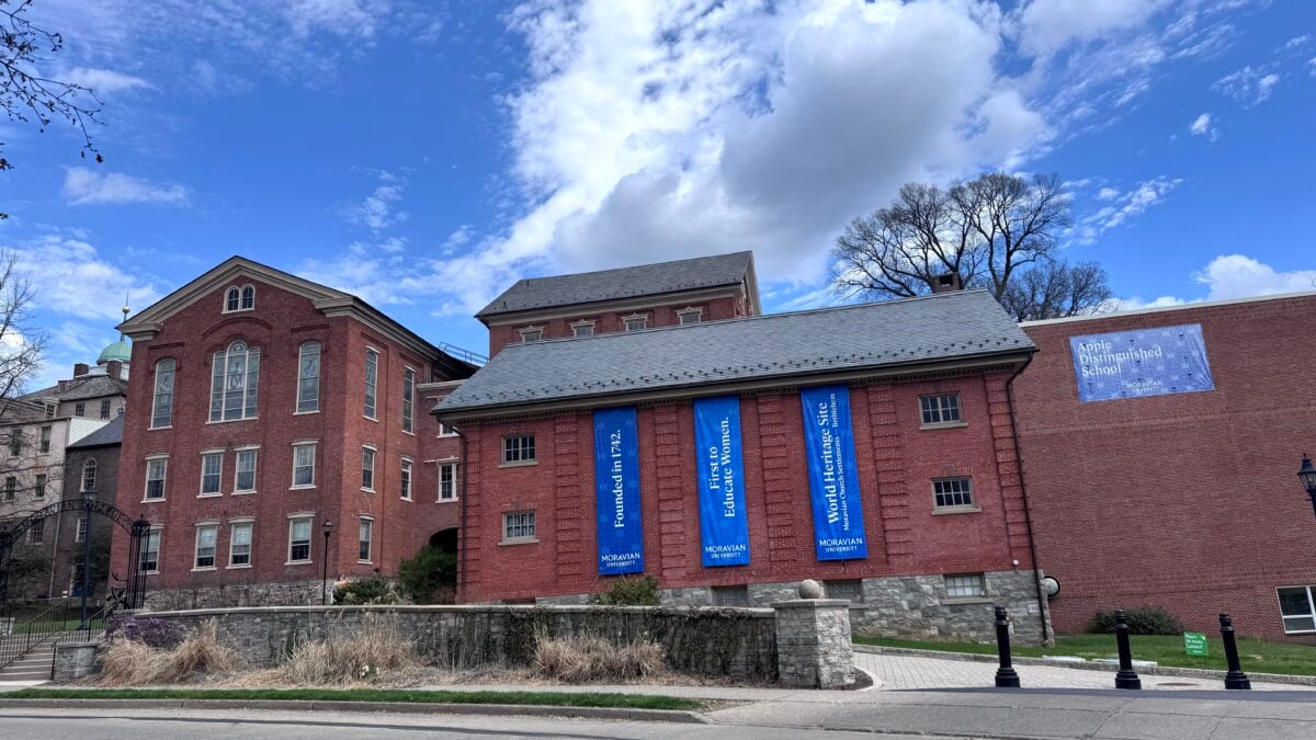 Brick buildings of Moravian University campus under a blue sky with white clouds.