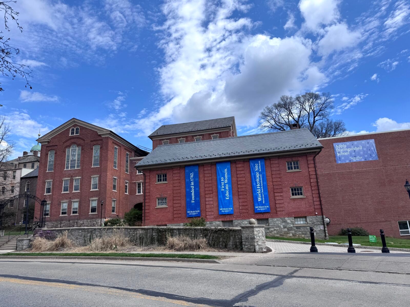 Brick buildings of Moravian University campus under a blue sky with white clouds.