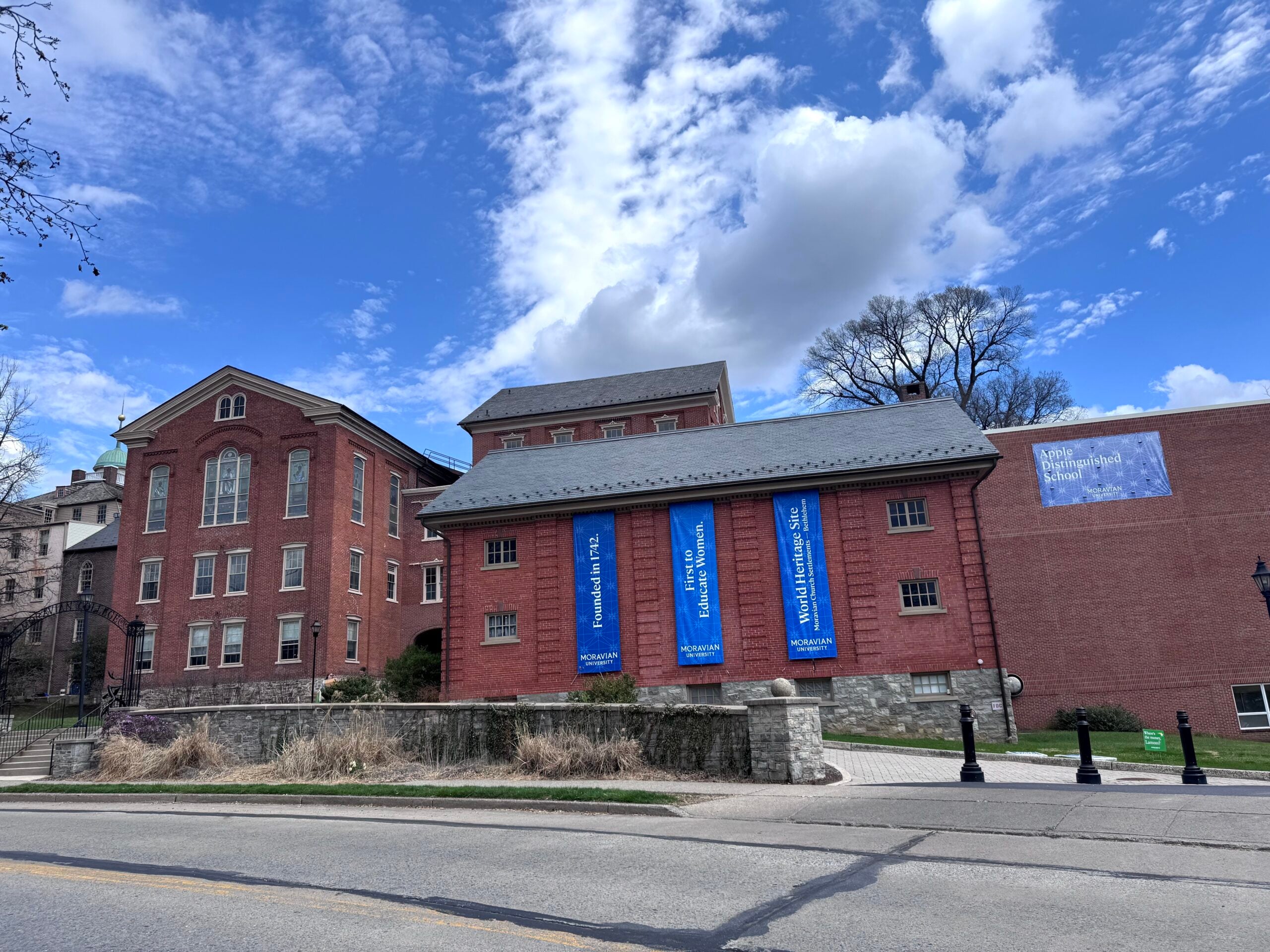 Brick buildings of Moravian University campus under a blue sky with white clouds.