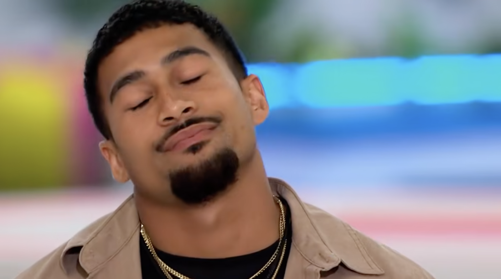 Sean Reifel, a man with a goatee and gold chains, closes his eyes and tilts his head slightly.