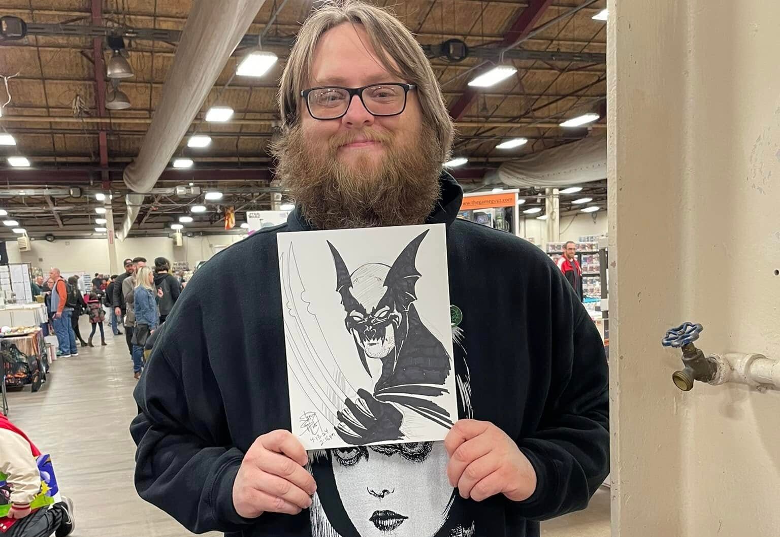 A fan holds up a black-and-white comic-style sketch by Jim Balent at the Lehigh Valley Comic Convention.
