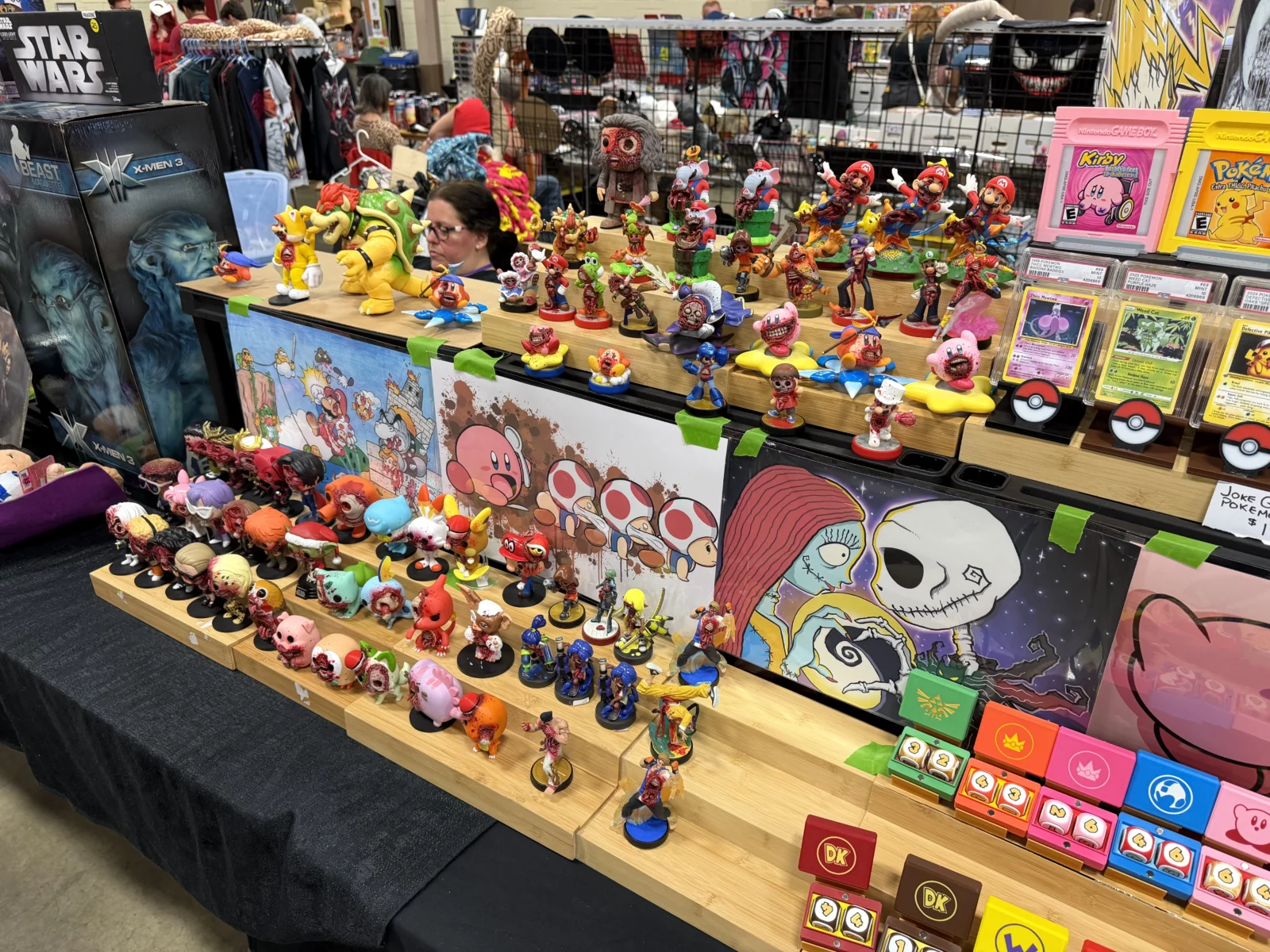 A vendor table displays many pop culture figurines, including zombie characters, and framed trading cards.