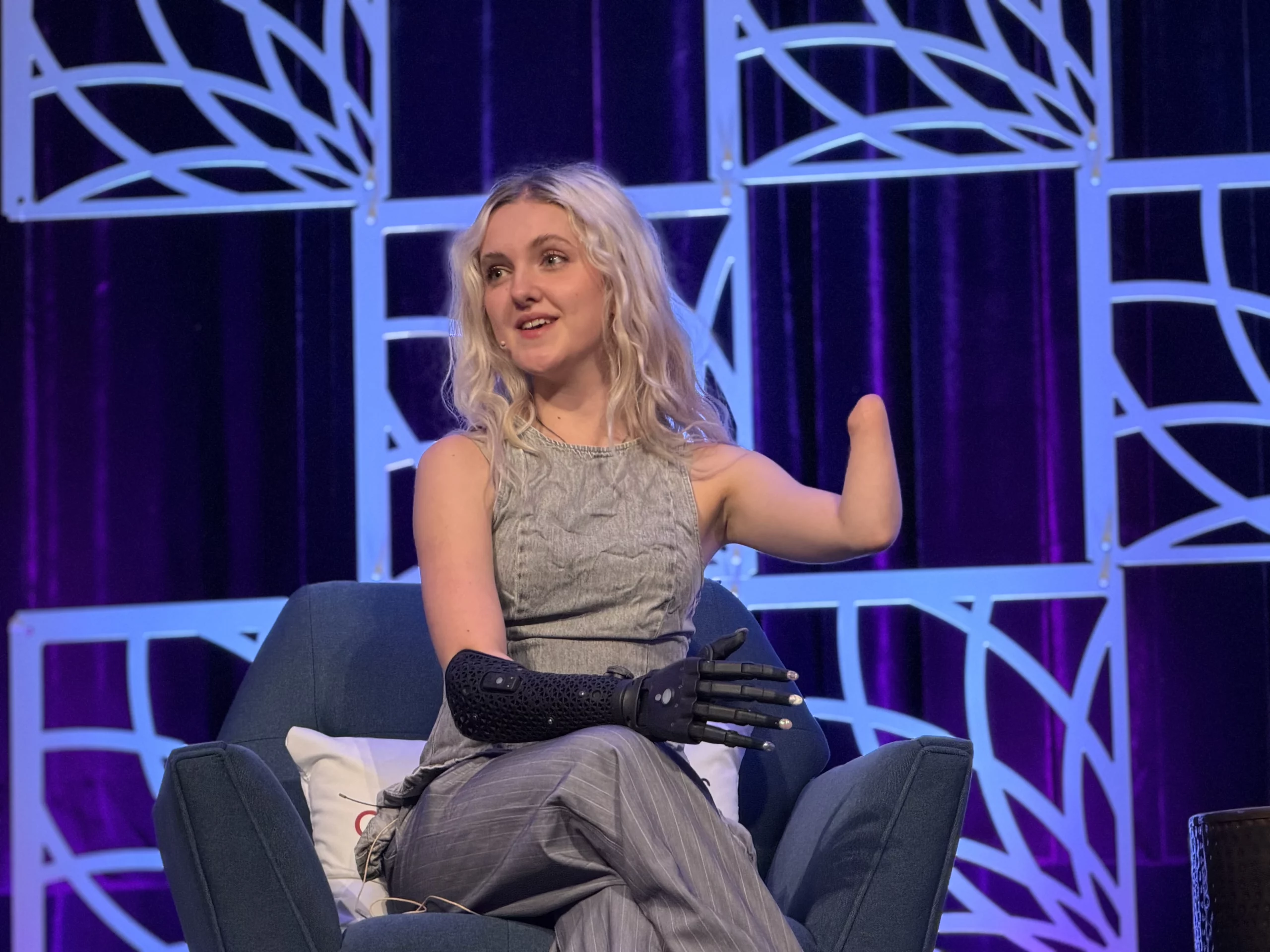 Tilly Lockey sits in a chair, wearing a black prosthetic hand on her left arm.