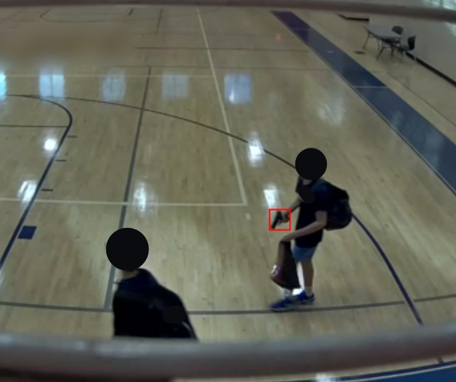 A security camera view of a gym floor shows two people with blacked-out faces; a small red box surrounds a handgun one of them holds.