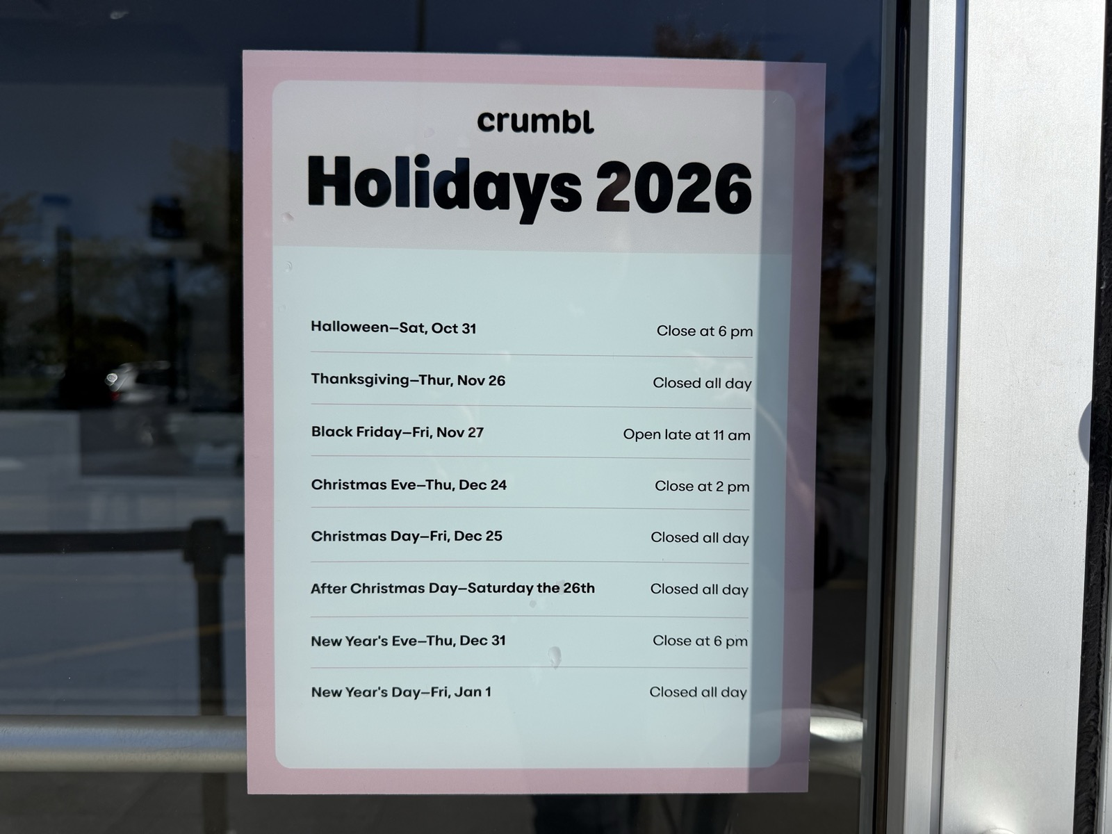 A printed Crumbl sign titled Holidays 2026 listing early closings and closed days from Oct. 31 to Jan. 1.