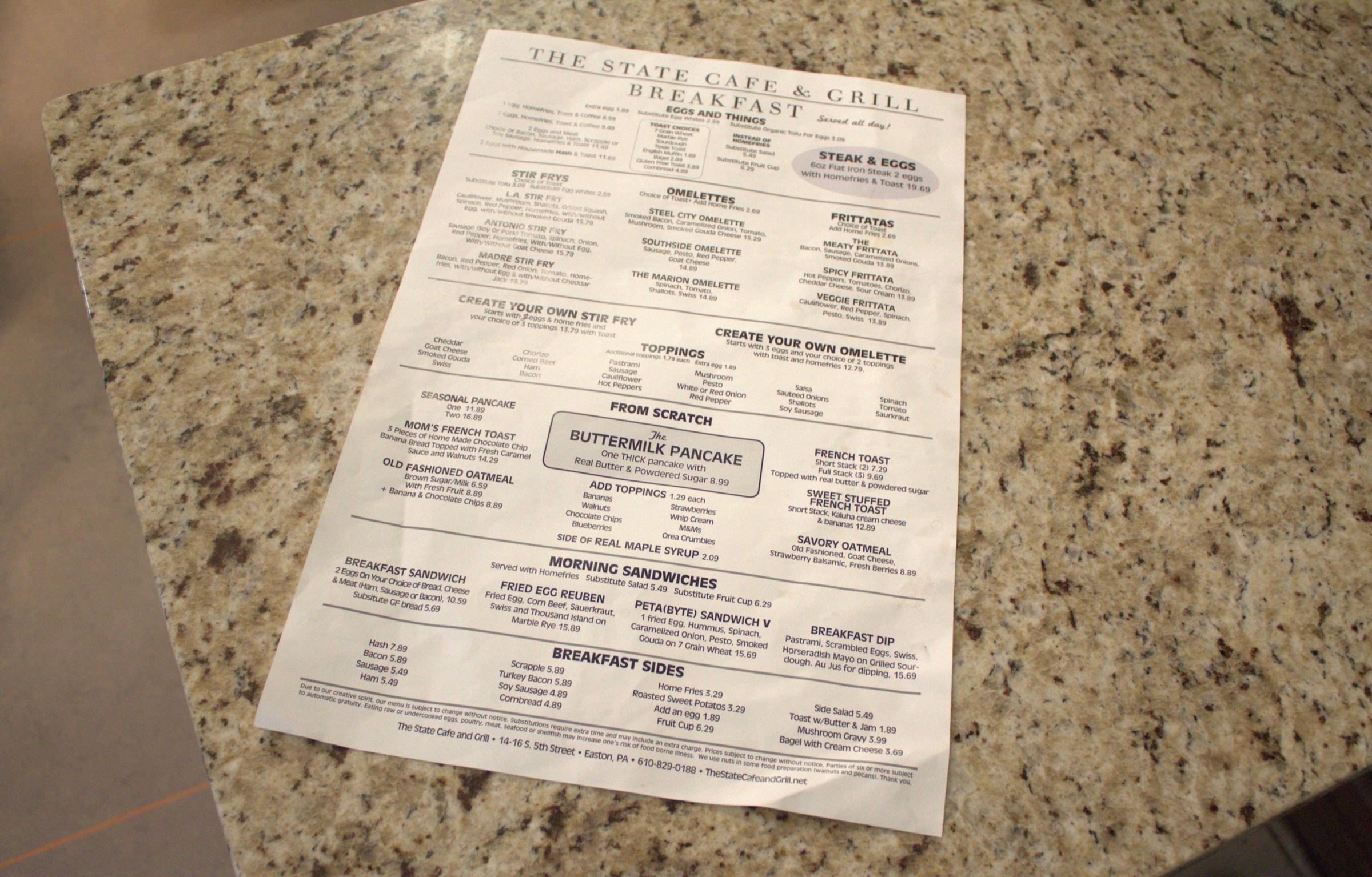 A printed breakfast menu lies on a granite counter.
